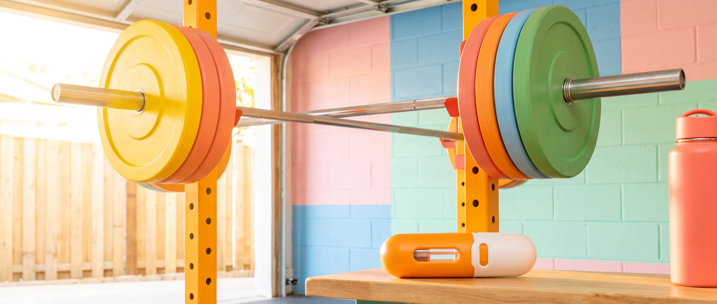 A barbell with coloured plates in a bright home gym, a plain injection pen on a bench